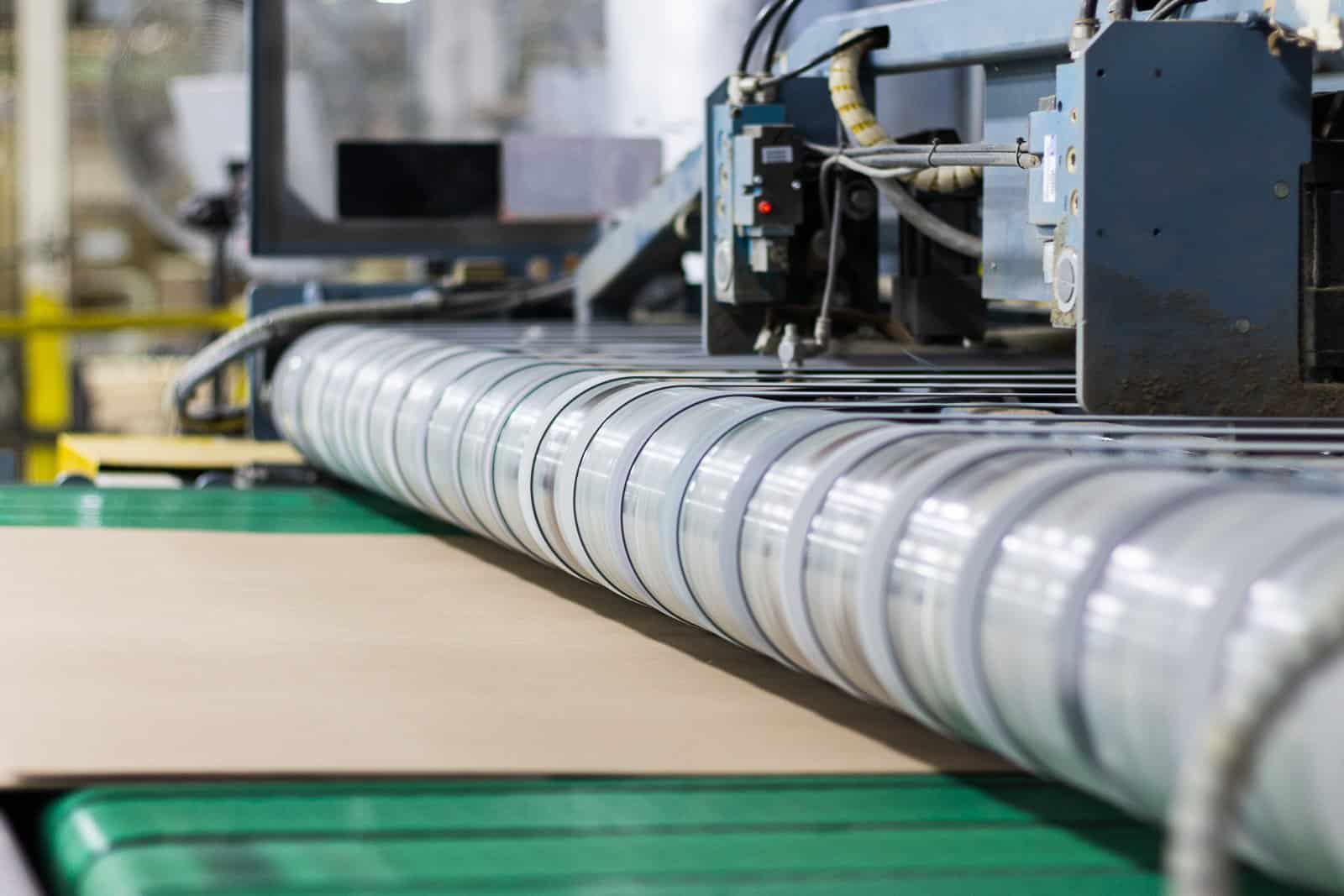 Laminated paperboard running through the nip of the solid fibre laminator